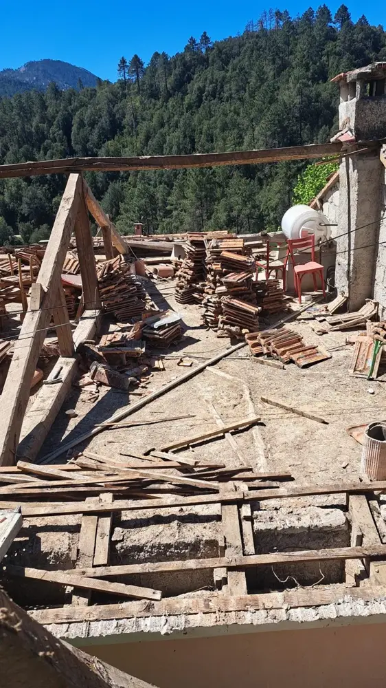 Charpente en chantier avec tuiles déposées, montagnes en arrière-plan